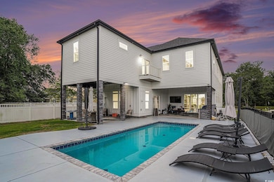 Back of house at dusk featuring a patio area, a ba