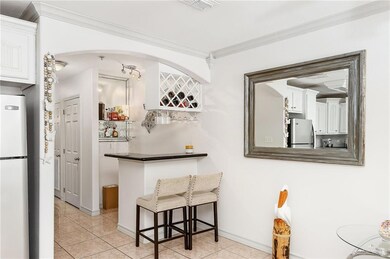 Kitchen featuring a breakfast bar area, white cabinets, stainless steel refrigerator, fridge, and light tile patterned flooring