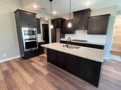Kitchen with stainless steel appliances, backsplash, dark wood finished floors, light stone countertops, and recessed lighting