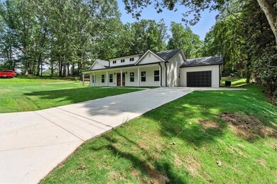 Modern inspired farmhouse featuring driveway, an attached garage, a front yard, board and batten siding, and a porch