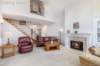 Carpeted living area featuring high vaulted ceiling, a tile fireplace, and stairway