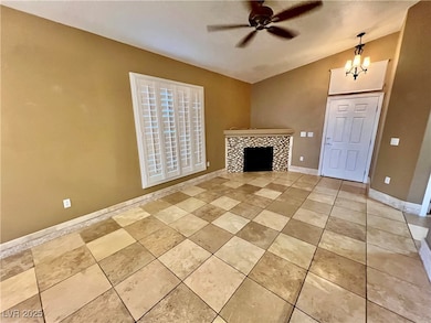 Unfurnished living room featuring lofted ceiling, a tiled fireplace, a ceiling fan, a chandelier, and light tile patterned flooring