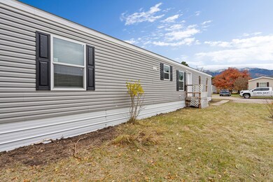 Side view showing the front entry and windows with mountains visible in the distance