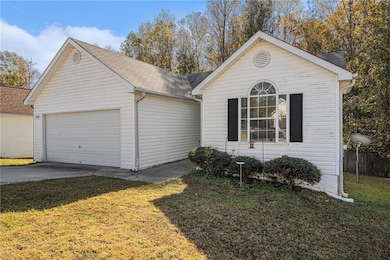 View of front of property with concrete driveway, a front lawn, an attached garage, and a shingled roof