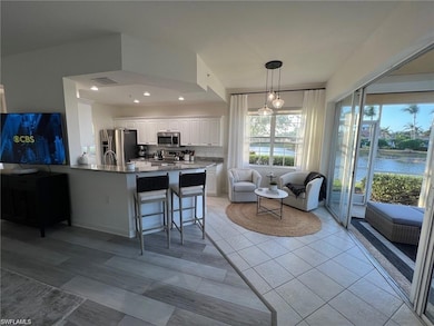 Kitchen with a peninsula, appliances with stainless steel finishes, white cabinetry, a breakfast bar area, and a water view
