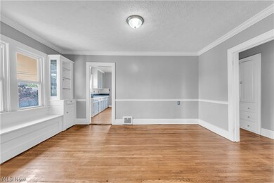 Empty room featuring a textured ceiling, ornamental molding, and light wood-type flooring