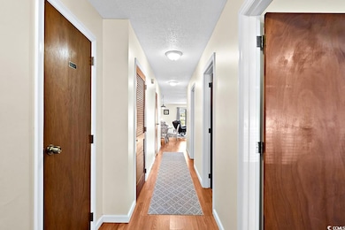 Corridor with a textured ceiling and light hardwoo