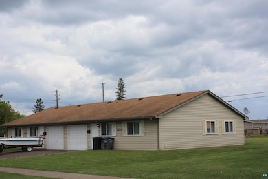 View of front of property featuring an attached garage, driveway, a front lawn, and a shingled roof
