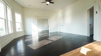 Empty room featuring dark wood-style flooring and ceiling fan