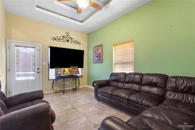 Tiled living room with a tray ceiling and a ceiling fan