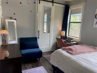 Bedroom with wood finished floors and a barn door