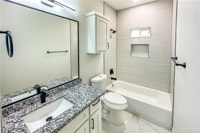 Full bathroom with tiled shower / bath, tile flooring, toilet, and vanity