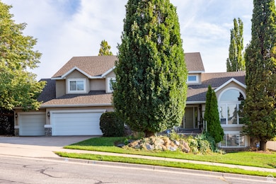 View of front of house featuring roof with shingles, concrete driveway, stone siding, a front lawn, and stucco siding