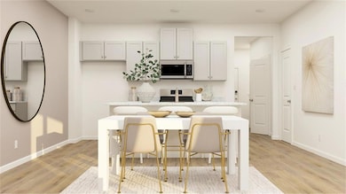 Kitchen with a breakfast bar, stove, light hardwood / wood-style floors, and an island with sink