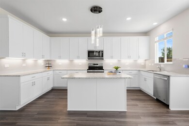 Kitchen featuring appliances with stainless steel finishes, a kitchen island, white cabinetry, backsplash, and hanging light fixtures