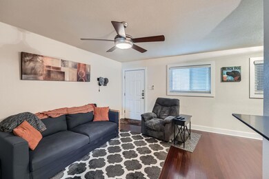 Living area with ceiling fan, baseboards, and woo