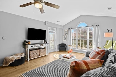 Living room featuring lofted ceiling, wood finished floors, and a ceiling fan