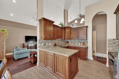Kitchen featuring tasteful backsplash, light stone counters, a peninsula, light wood finished floors, and open floor plan