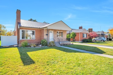 View of front of house with a front yard, brick siding, a porch, and a chimney