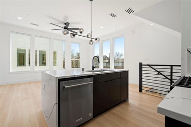 Kitchen featuring a center island with sink, visible vents, hanging light fixtures, stainless steel dishwasher, and a sink