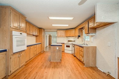 Inside, the kitchen awaits with extensive cabinetry and a center island under warm lighting. Set at the heart of the home, it flows out to living areas on both ends.
