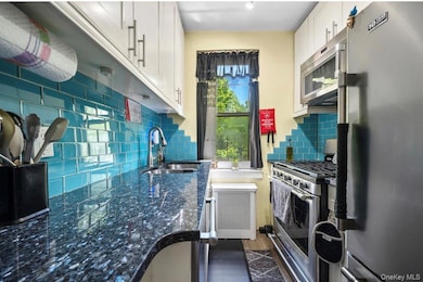 Kitchen with appliances with stainless steel finishes, tasteful backsplash, and white cabinetry