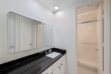 Updated primary bathroom features a shower with Daltile subway tile and a new glass door. Ample countertop space and a large mirror add both function and style.