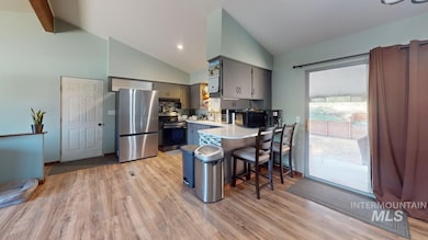 Kitchen with stainless steel appliances, a peninsula, gray cabinetry, light countertops, and light wood finished floors