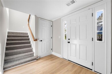 Foyer with stairway, visible vents, baseboards, an