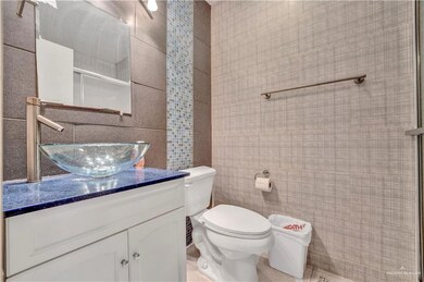 Bathroom featuring tile walls, vanity, toilet, and a shower