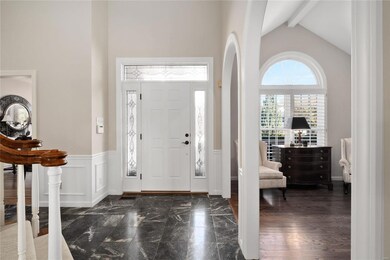 2-story entry foyer with marble flooring, triple crown molding, wainscoting & arched entries into living room.