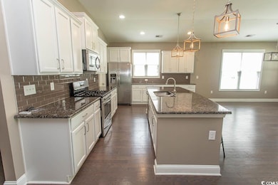 Kitchen with appliances with stainless steel finishes, dark wood-type flooring, white cabinetry, backsplash, and recessed lighting