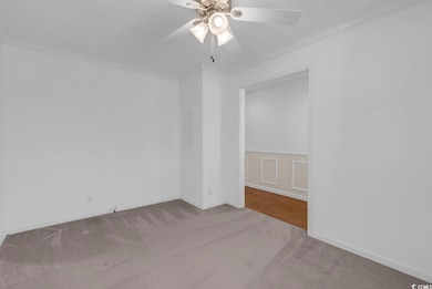 Unfurnished room featuring carpet flooring, crown molding, a ceiling fan, and tile patterned flooring
