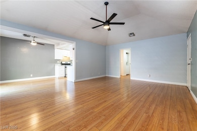 Unfurnished living room featuring ceiling fan, light wood-style flooring, and vaulted ceiling