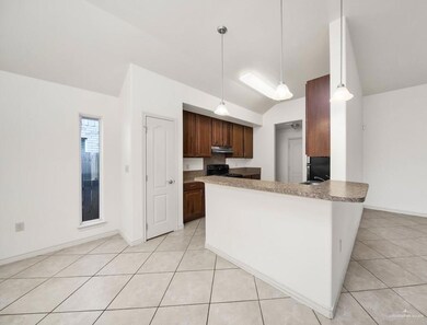 Kitchen with kitchen peninsula, vaulted ceiling, decorative light fixtures, light tile flooring, and stove
