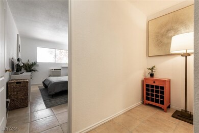 Corridor featuring light tile patterned flooring, a textured ceiling, and a textured wall