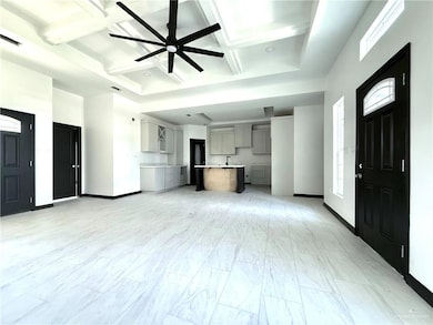 Unfurnished living room with coffered ceiling, a ceiling fan, baseboards, beamed ceiling, and light marble finish flooring
