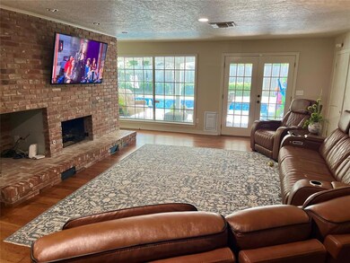 Living area featuring wood finished floors, plenty of natural light, a brick fireplace, a textured ceiling, and french doors