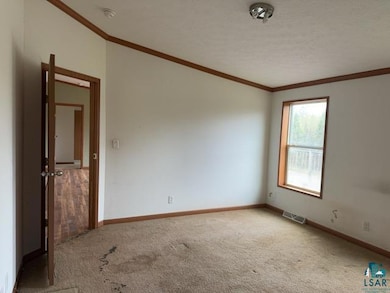 Carpeted spare room with ornamental molding, baseboards, and a smoke detector
