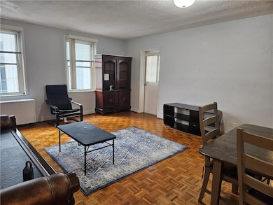 Living area with a textured ceiling and radiator