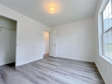 Unfurnished room featuring wood finished floors, a textured ceiling, and baseboards