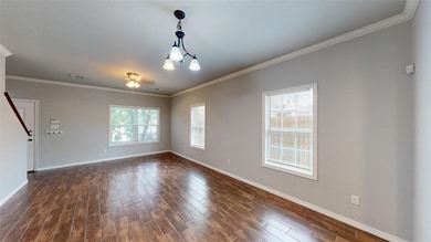 Spare room with crown molding, dark wood finished floors, healthy amount of natural light, and a chandelier