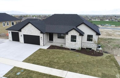 View of front of property featuring stone siding, an attached garage, driveway, a front yard, and covered porch