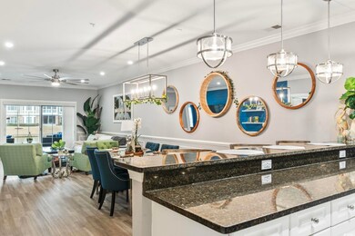 Kitchen with ornamental molding, white cabinets, a kitchen bar, decorative light fixtures, and dark stone counters