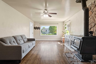 Living area featuring a wood stove, ceiling fan, and dark wood finished floors