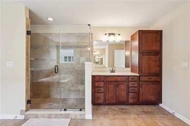 Full bath with vanity, baseboards, a shower stall,