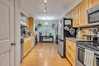 Kitchen featuring stainless steel appliances, light brown cabinets, light wood-type flooring, and tasteful backsplash