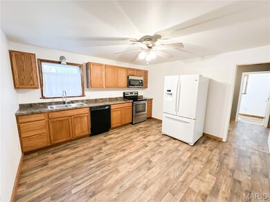 Kitchen with white refrigerator with ice dispenser, electric stove, brown cabinetry, and dark countertops