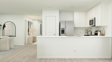Kitchen featuring appliances with stainless steel finishes, a peninsula, white cabinets, light wood-type flooring, and light countertops