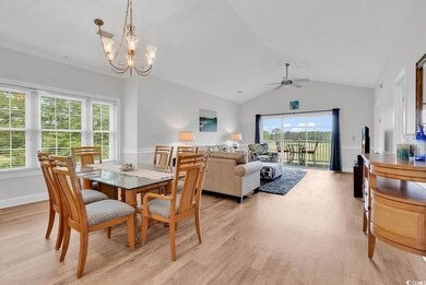 Dining room featuring light wood-style floors, ceiling fan, a chandelier, and vaulted ceiling